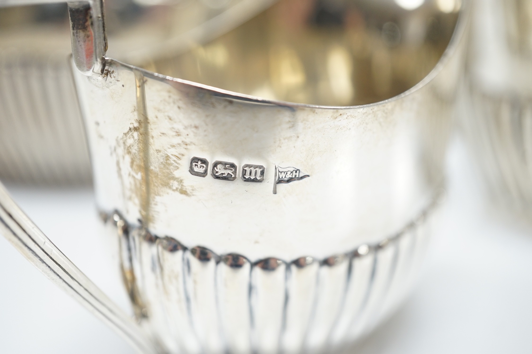 A matched early 20th century silver bachelor's three piece tea set, tea pot, James Dixon & Sons, Sheffield, 1920, cream and sugar, Walker & Hall, Sheffield, 1904, gross weight 14oz.